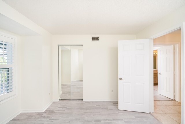 unfurnished bedroom with light wood-type flooring and a closet