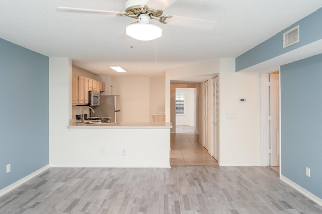 kitchen with stainless steel appliances, ceiling fan, light wood-type flooring, and kitchen peninsula