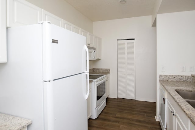 kitchen with white appliances, dark hardwood / wood-style floors, a textured ceiling, light stone counters, and white cabinetry