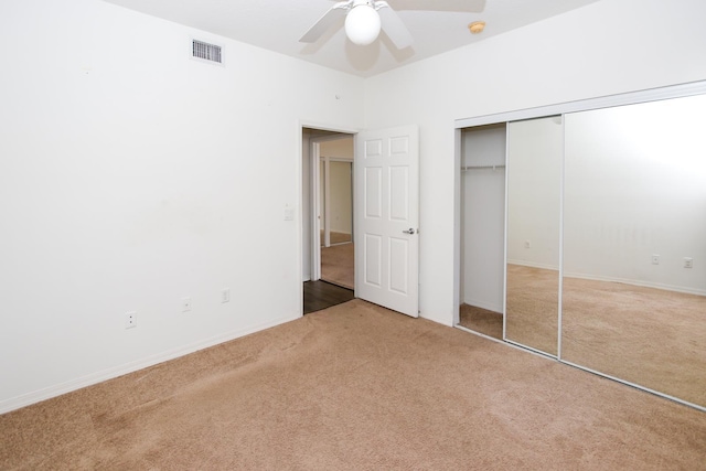 unfurnished bedroom featuring a closet, light colored carpet, and ceiling fan