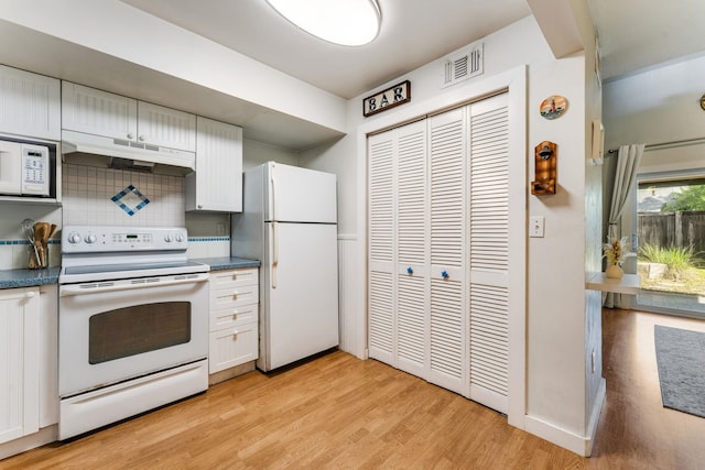 4502 Sandcastle Cir, Saint Augustine, FL 32084 - kitchen featuring white appliances, under cabinet range hood, light wood-style flooring, backsplash, and dark countertops