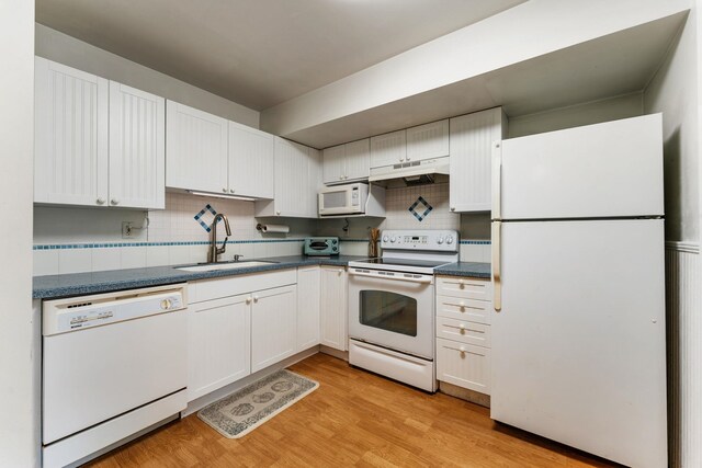 4502 Sandcastle Cir, Saint Augustine, FL 32084 - kitchen featuring white appliances, under cabinet range hood, dark countertops, light wood-type flooring, and tasteful backsplash
