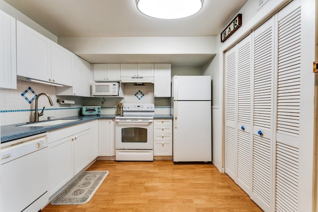 4502 Sandcastle Cir, Saint Augustine, FL 32084 - kitchen with white appliances, under cabinet range hood, backsplash, white cabinets, and dark countertops