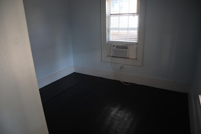 empty room featuring cooling unit and dark wood-type flooring