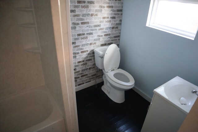 full bathroom with washtub / shower combination, vanity, toilet, and brick wall