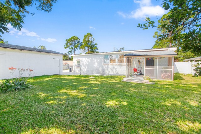 rear view of property featuring a lawn and a sunroom