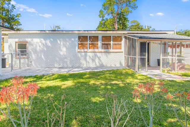 rear view of house with a yard and a sunroom