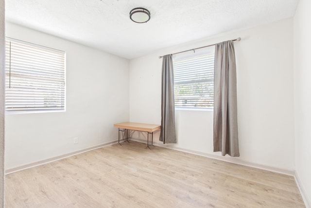 spare room featuring light hardwood / wood-style flooring and a textured ceiling