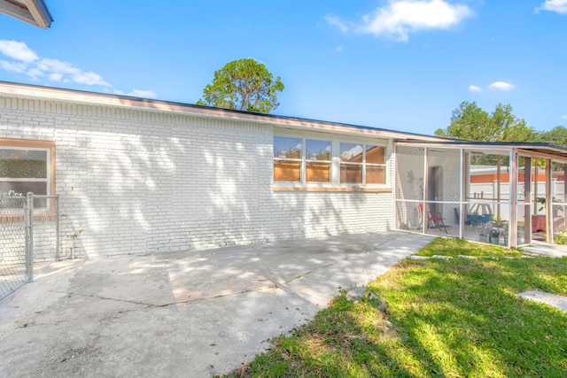 back of house featuring a sunroom and a lawn