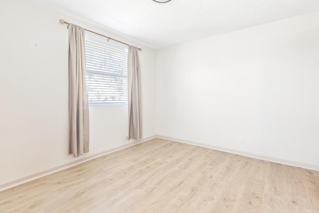 spare room with a textured ceiling and light hardwood / wood-style flooring