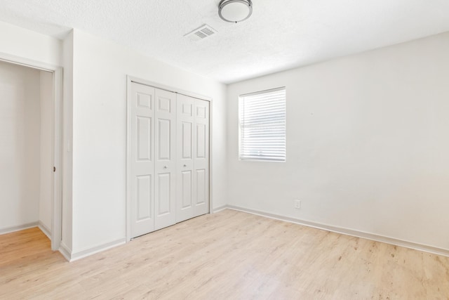 unfurnished bedroom with a closet, a textured ceiling, and light hardwood / wood-style flooring