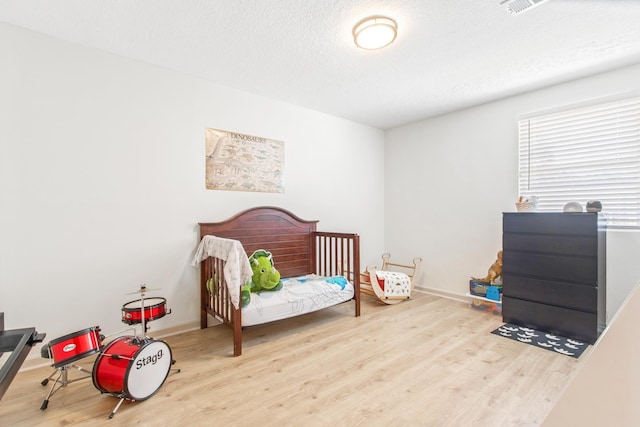 bedroom with a textured ceiling and light wood-type flooring