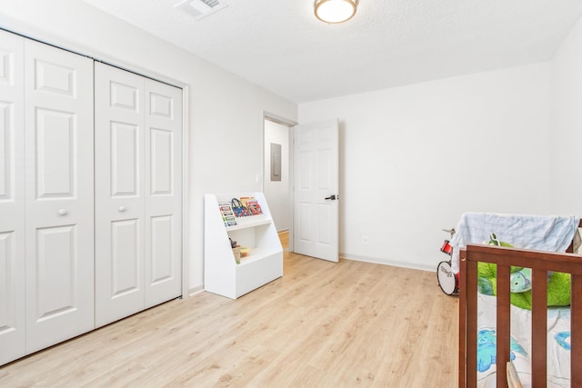 bedroom featuring light wood-type flooring, a textured ceiling, and a closet