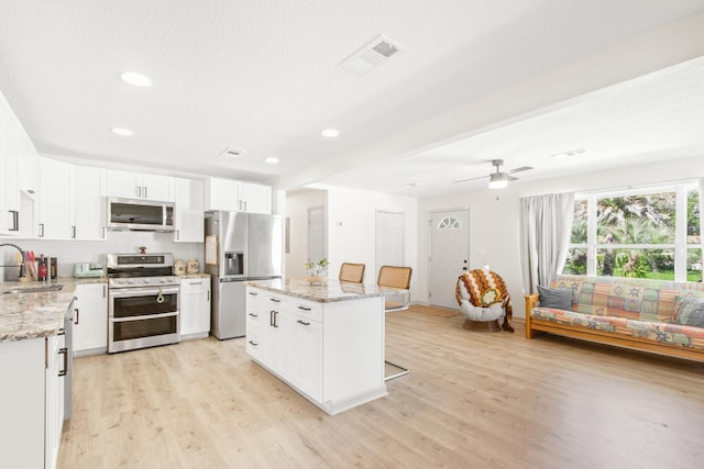 kitchen with a center island, white cabinets, sink, light hardwood / wood-style flooring, and stainless steel appliances