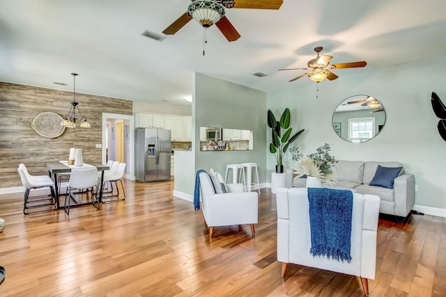 living room featuring wood walls, a notable chandelier, and light wood-type flooring