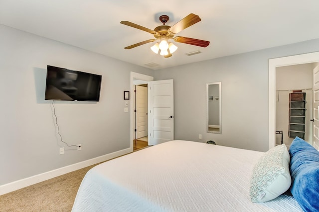 carpeted bedroom featuring a closet, a spacious closet, and ceiling fan