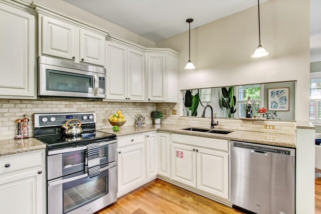 kitchen featuring sink, hanging light fixtures, light hardwood / wood-style floors, white cabinetry, and stainless steel appliances