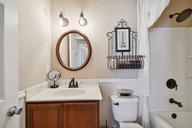 bathroom featuring toilet, a wainscoted wall, tub / shower combination, and vanity