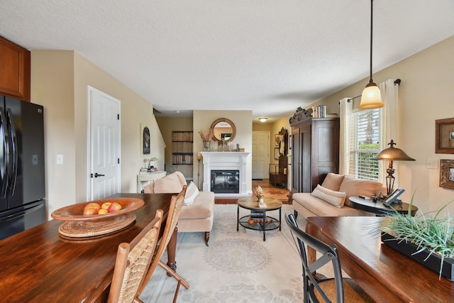 living area with light wood-type flooring, a glass covered fireplace, and a textured ceiling