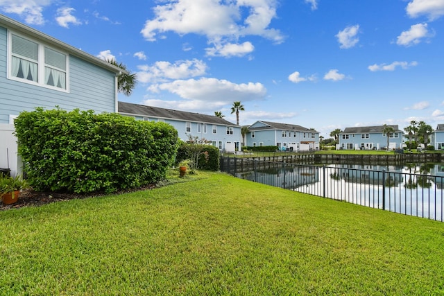 view of yard featuring a water view, fence, and a residential view