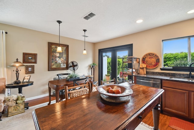 dining room with a textured ceiling, wood finished floors, visible vents, and baseboards