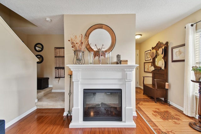 unfurnished living room featuring baseboards, a textured ceiling, a multi sided fireplace, and wood finished floors