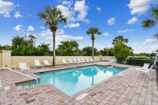 community pool with fence and a patio