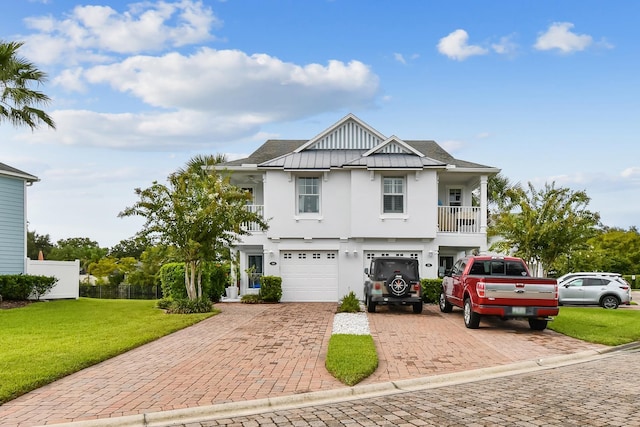 view of front of house featuring a balcony, driveway, stucco siding, a front lawn, and board and batten siding