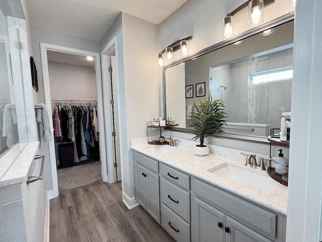 bathroom featuring vanity, hardwood / wood-style flooring, a textured ceiling, and tiled shower