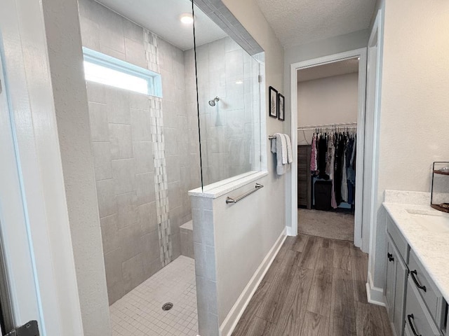 bathroom featuring vanity, tiled shower, hardwood / wood-style floors, and a textured ceiling