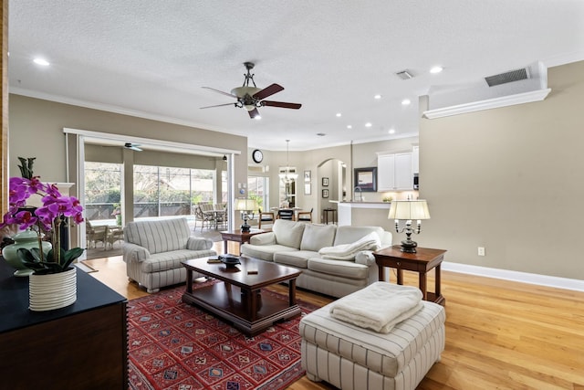 living room with ornamental molding, ceiling fan, a textured ceiling, and light hardwood / wood-style floors