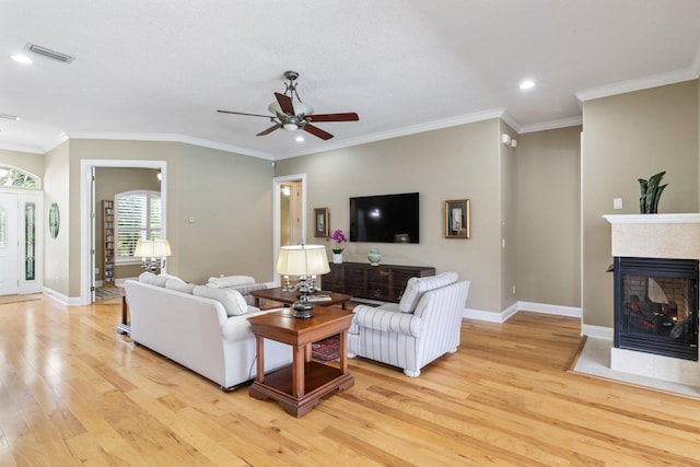 living room featuring a multi sided fireplace, ornamental molding, ceiling fan, and light hardwood / wood-style flooring