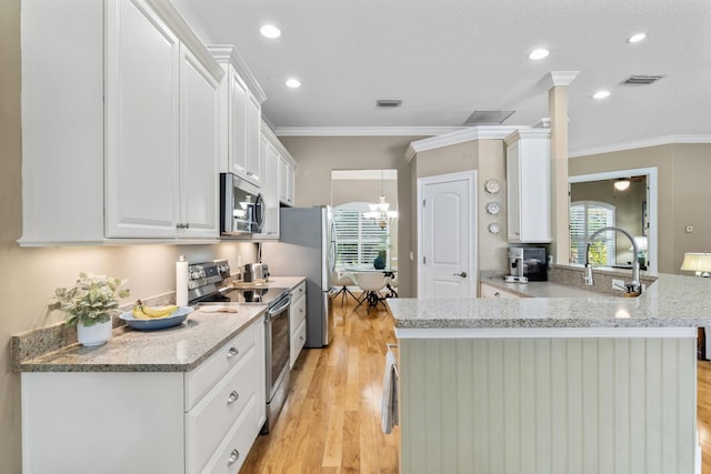 kitchen featuring light stone counters, light wood-type flooring, appliances with stainless steel finishes, kitchen peninsula, and white cabinets