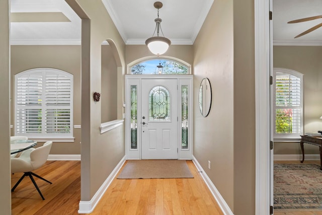 foyer entrance with ornamental molding and light hardwood / wood-style floors