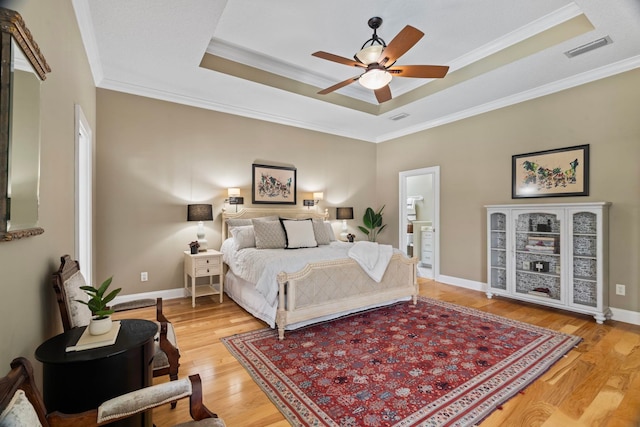 bedroom with a raised ceiling, ornamental molding, ceiling fan, and light hardwood / wood-style floors