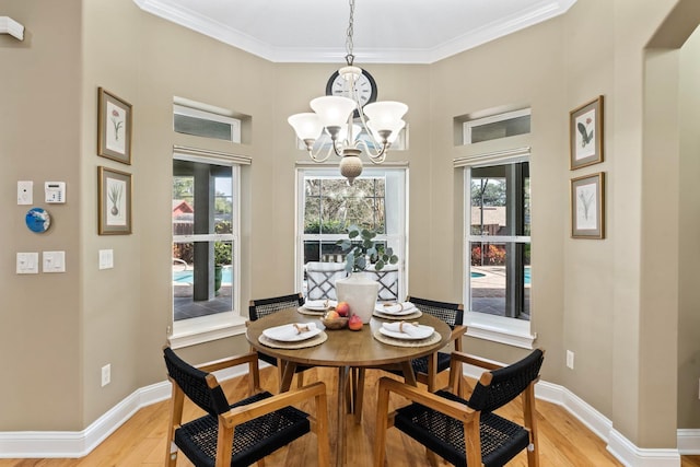 dining space featuring a high ceiling, crown molding, light wood-type flooring, and a chandelier