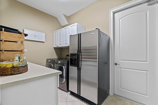 kitchen with light tile patterned floors, stainless steel fridge with ice dispenser, washing machine and dryer, and white cabinets