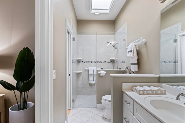 bathroom featuring toilet, a skylight, a tile shower, vanity, and tile patterned flooring