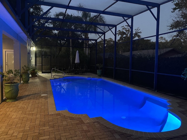 pool at dusk with a patio area and glass enclosure