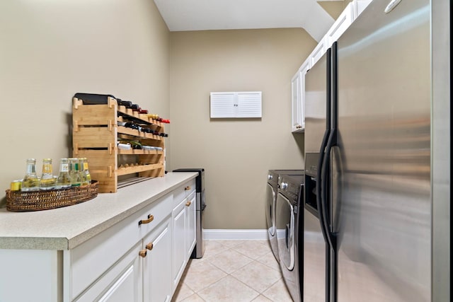 laundry area featuring independent washer and dryer, light tile patterned floors, and cabinets