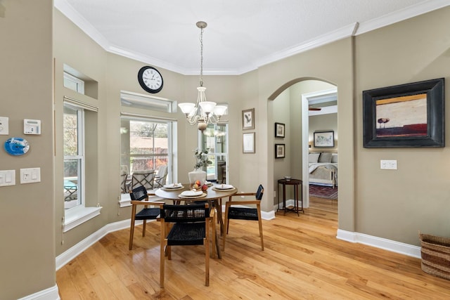 dining area with ornamental molding, an inviting chandelier, and light hardwood / wood-style floors