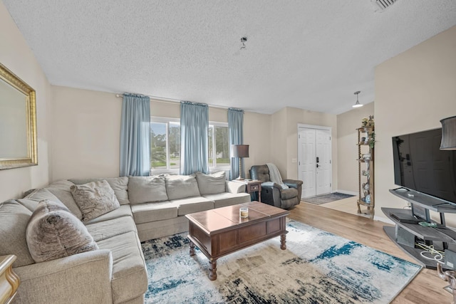 living room with a textured ceiling and light wood-type flooring