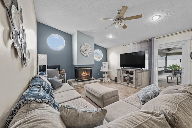 living room featuring a multi sided fireplace, a textured ceiling, vaulted ceiling, and ceiling fan