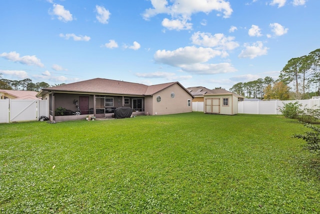 rear view of house featuring a yard, a storage shed, and a sunroom