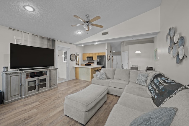 living room featuring ceiling fan, high vaulted ceiling, light hardwood / wood-style floors, and a textured ceiling