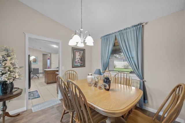 dining area featuring light hardwood / wood-style floors, lofted ceiling, and an inviting chandelier