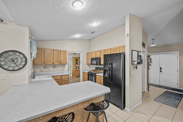 kitchen featuring lofted ceiling, black appliances, sink, light tile patterned flooring, and kitchen peninsula