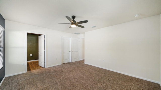 unfurnished bedroom featuring dark colored carpet, a closet, and ceiling fan