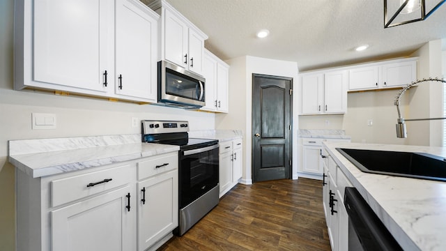 kitchen with light stone counters, white cabinetry, and stainless steel appliances