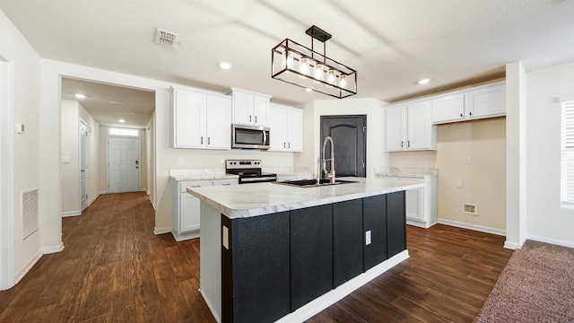 kitchen with appliances with stainless steel finishes, sink, white cabinetry, and an island with sink